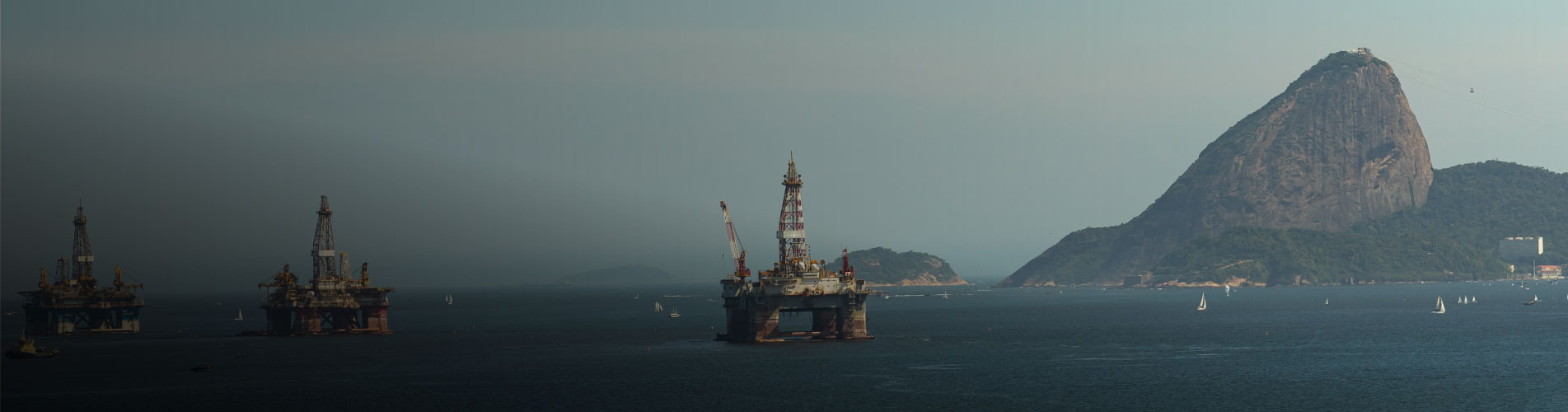 Imagem de plataformas de petróleo na Baía de Guanabara com vista para o Pão de Açúcar